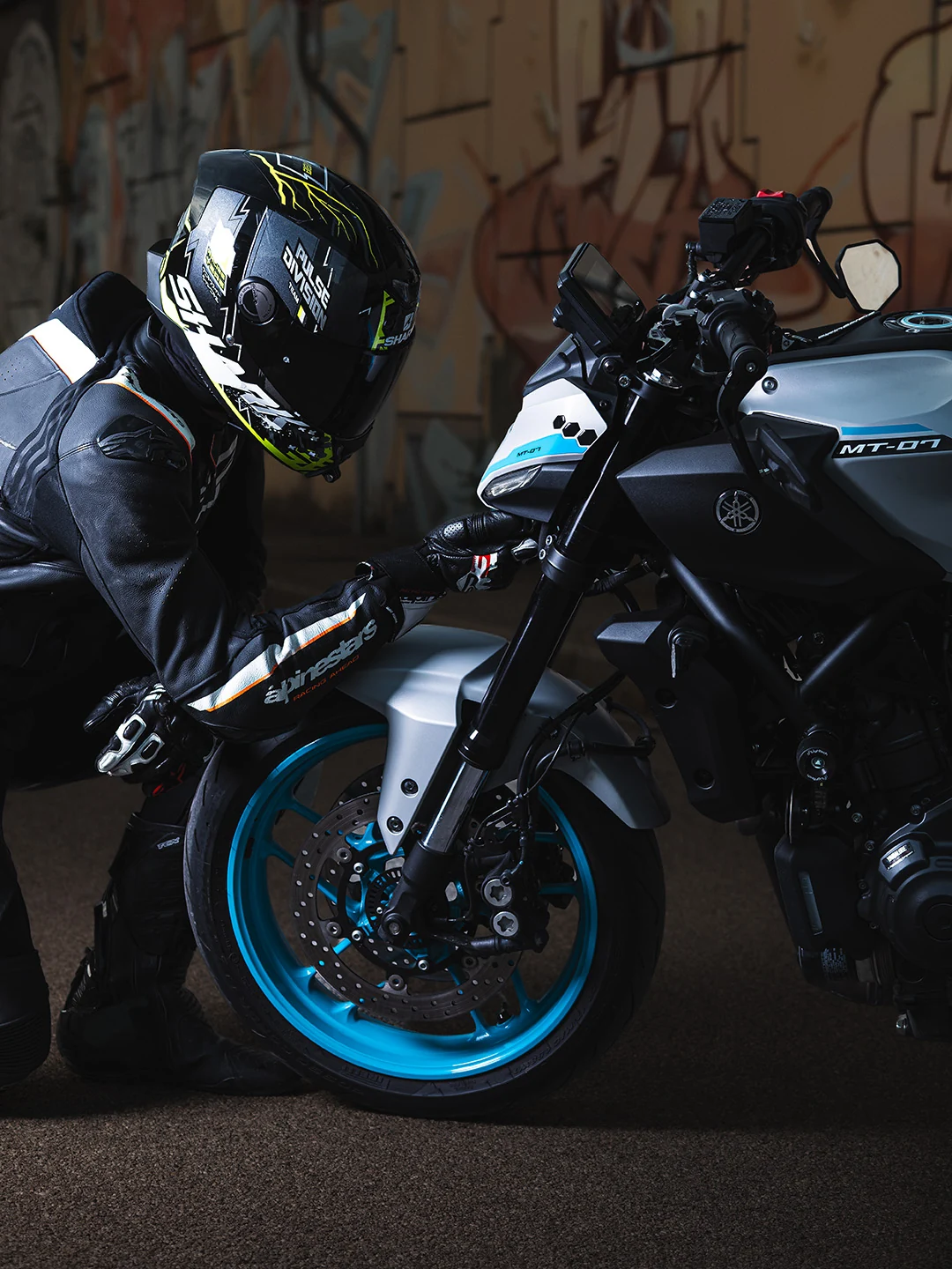 Motociclista con casco chino vicino alla ruota anteriore turchese della Yamaha MT-07